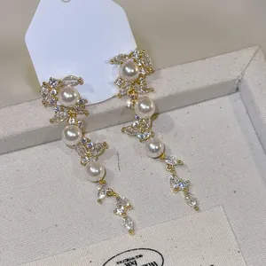 Close-up of elegant leaf tassel earrings featuring marquise zircons and white pearls