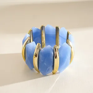 Macro detail view of blue acrylic and gold-toned irregular geometric elastic bracelet