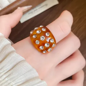 Detailed view of a dome-shaped amber resin ring inlaid with sparkling clear rhinestones