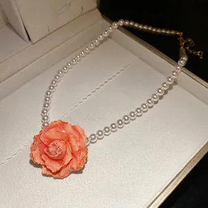 Elegant white pearl necklace featuring a large coral pink rose flower centerpiece pendant