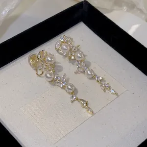 Detailed macro view of elegant leaf tassel clip-on earrings with pearls and zircons