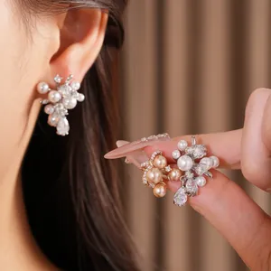 Eleganti orecchini a perno con farfalla e perle in argento e oro con zirconi lucenti.