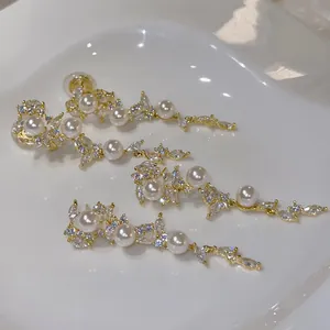 Close-up of elegant leaf tassel earrings with white pearls and sparkling zircons