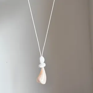Primo piano della collana con pendente geometrico minimalista e dettaglio in pietra.