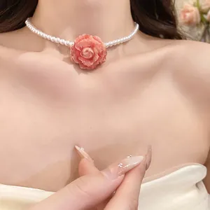 Elegant close-up of a pearl choker necklace featuring a delicate pink rose flower pendant