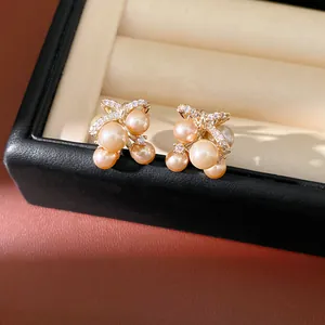 Eleganti orecchini a perno a farfalla dorati con perle lucenti e zirconi scintillanti.
