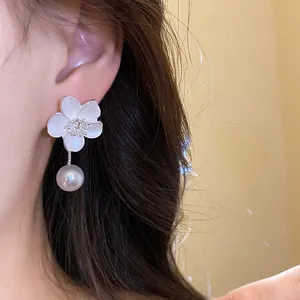 Close-up of vintage flower drop earrings with white pearl and rhinestone center