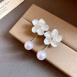 Detailed view of French vintage floral earrings with rhinestone centers and pearl drops.