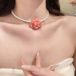 Close-up detail of elegant pearl necklace featuring a delicate pink rose flower pendant