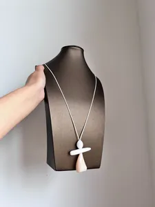 Dettaglio di un ciondolo ad angelo geometrico astratto su una lunga collana bianca