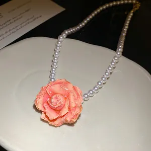 Close-up of elegant pearl necklace featuring a detailed pink rose floral pendant