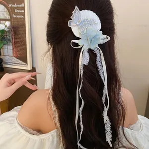 Elegant blue flower butterfly hair clip with long lace tassels shown on long brown hair