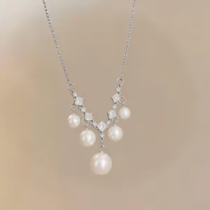 Detailansicht einer eleganten silbernen Halskette mit Zirkonia und hängenden weißen Perlen