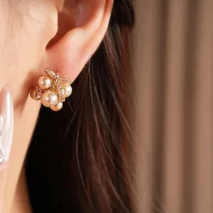 Dettaglio di orecchini a perla e fiocco di zircone con un elegante design a grappolo.