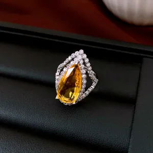 Makroaufnahme eines gelben Zirkonia-Rings im Birnenschliff mit Pavé-Fassung auf schwarzem Display