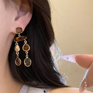 Detailed view of retro Maillard style amber crystal tassel earrings on an ear.