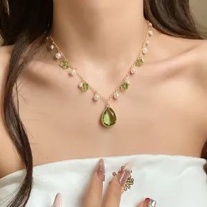 Close-up of elegant vintage green pearl necklace with water-drop crystal pendant on model