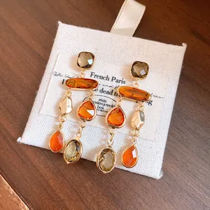 Detailed view of vintage Maillard style orange crystal tassel earrings on linen pouch