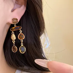 Close-up detail view of Maillard style earrings with brown teardrop crystal tassels