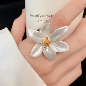 Detailed close-up of elegant vintage white flower open ring with gold stamen on finger