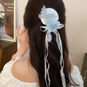 Detailed view of a sweet blue fabric flower hair clip with butterfly and lace tassels