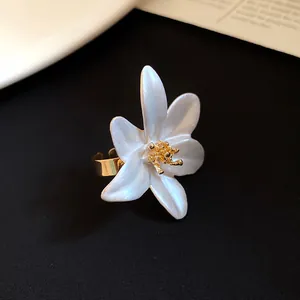 Detailed view of vintage white enamel flower open ring with gold stamen on black background