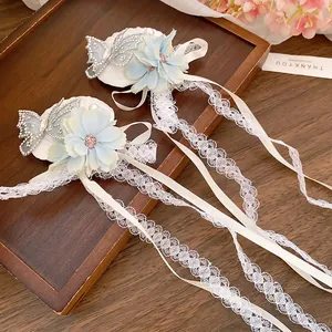 Detail of fabric flower hair clip with rhinestone butterfly and long lace tassels