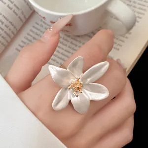 Detailed close-up of a vintage white flower ring with an adjustable gold band