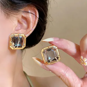 Elegant square smoky grey glass stud earrings with gold-plated trim shown on model