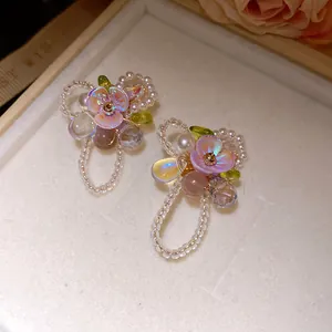 Close-up detail showing intricate floral stud earrings with purple petals and pearls