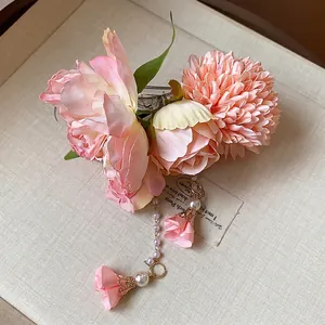 Barrette à cheveux élégante fleur en tissu rose avec perles et détails en filigrane doré.
