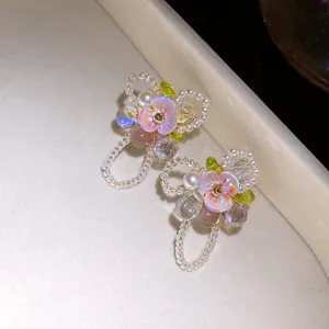 Detailed view of floral stud earrings with pearls, cat-eye stones, and iridescent petals