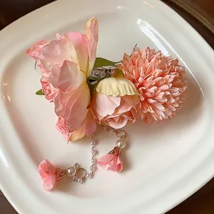 Pince à cheveux élégante avec fleurs en tissu rose et glands en perles sur une assiette