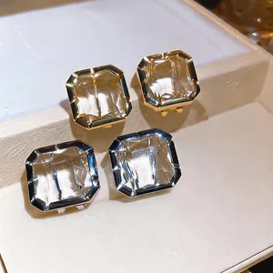 Detail macro view of square faceted glass stud earrings in gold and silver finishes.