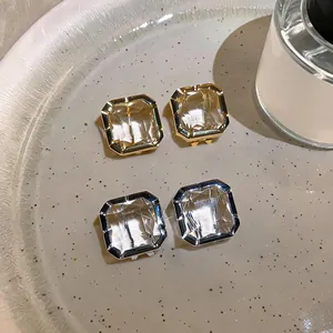 Detailed macro view of square glass crystal stud earrings in gold and silver finish
