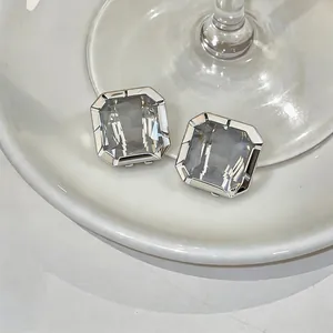 Exquisite close-up of minimalist square grey glass stud earrings with silver-toned settings