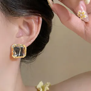 Macro detail of elegant square glass stud earrings with gold plating worn on ear