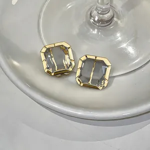 Exquisite close-up detail of minimalist square glass stud earrings with gold plated frame