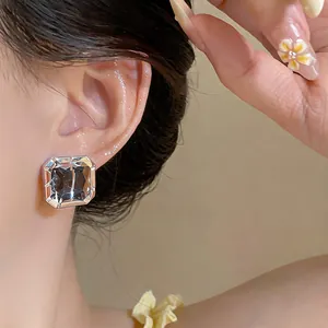 Detailed close-up of a minimalist square glass stud earring with silver needle on ear