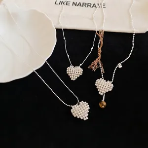 Minimalist silver beaded heart pendant necklaces with elegant chains on black surface