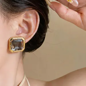 Close-up detail of elegant square smoke grey crystal stud earring with gold-tone frame