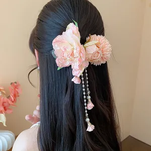 Détail macro de fleurs en tissu rose et glands de perles sur une pince à cheveux chic