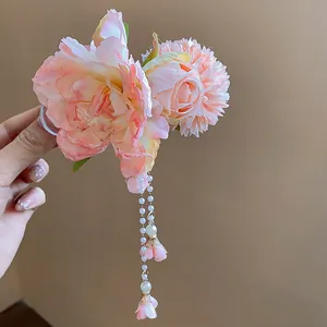Détail de fleurs en tissu rose et pompons en perles sur une pince à cheveux élégante