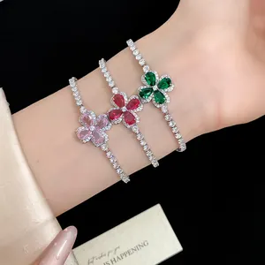 Close-up of three clover-shaped bracelets with pink, red, and green zircons on a wrist