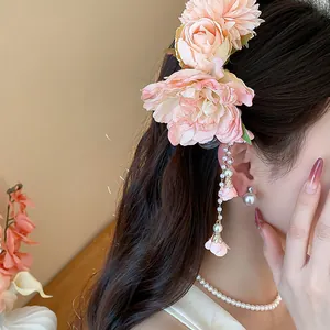 Vue détaillée d'une pince à cheveux fleur rose avec d'élégants glands en perles sur un modèle.