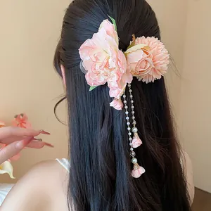 Vue détaillée d'une pince à cheveux fleur rose en tissu avec pampilles de perles.