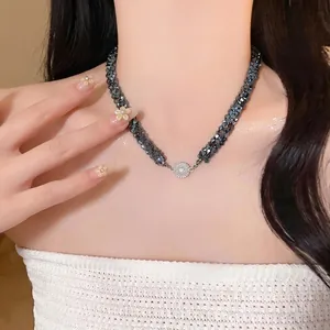 Collier élégant en perles de verre noires tressées avec pendentif central en strass brillant.