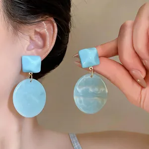 Orecchini pendenti geometrici in resina azzurra con texture marmorizzata chic.
