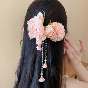 Vue arrière d'une pince à cheveux fleur en tissu rose avec glands de perles sur cheveux noirs