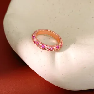 Detailed close-up of an elegant rose gold eternity ring set with pink and white zircon stones.